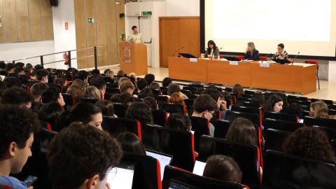 Estudiantes sentados y sentadas en las sillas del aula magna de la Facultad de Comunicación.